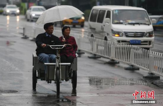資料圖：民眾在雨中出行。<a target=