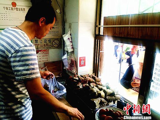 圖為凌君道正在將粽子裝袋進(jìn)行售賣?！「呖档?攝