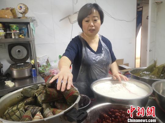鄭春玲將兩張大粽葉窩成漏斗狀，填上糯米，放上兩粒紅棗，再加一片小粽葉，用棉線纏繞綁好，一個(gè)紅棗粽就成了，用時(shí)僅8秒?！「呖档?攝